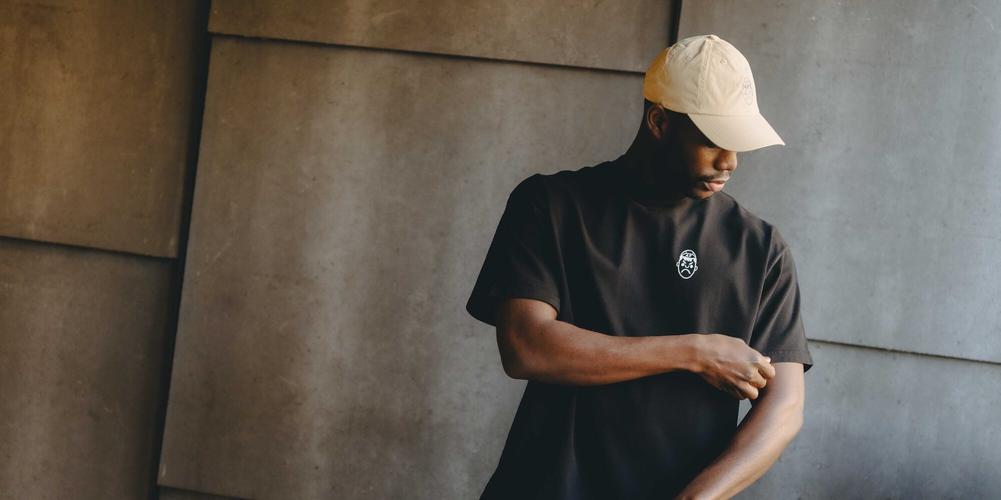 A man wearing a heavy oversized black t-shirt and a cream Angry Pablo cap