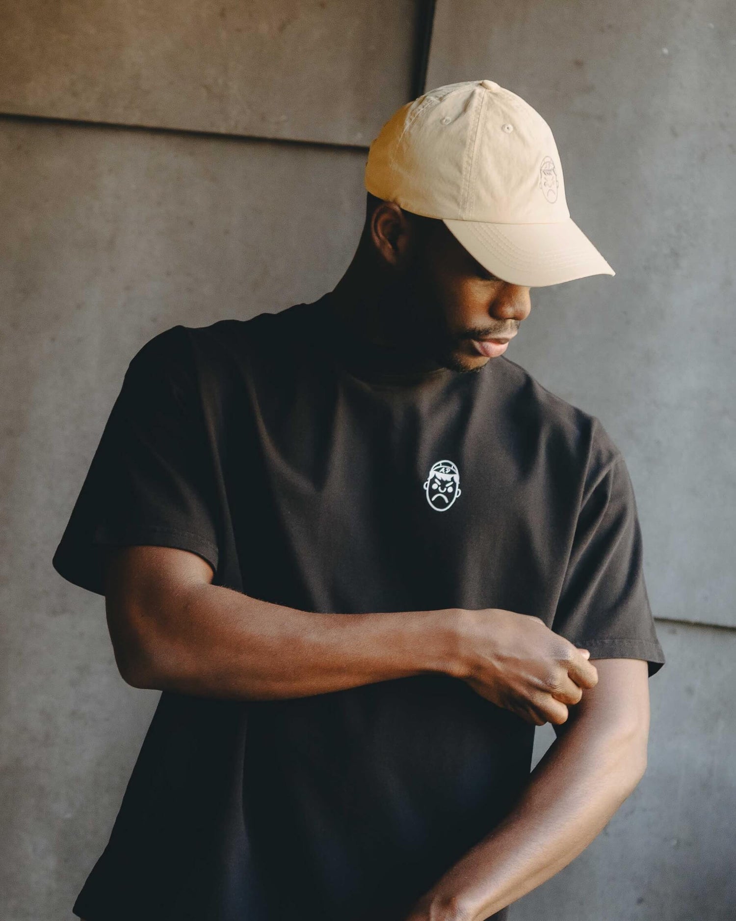 A man wearing a heavy oversized black t-shirt and a cream Angry Pablo cap