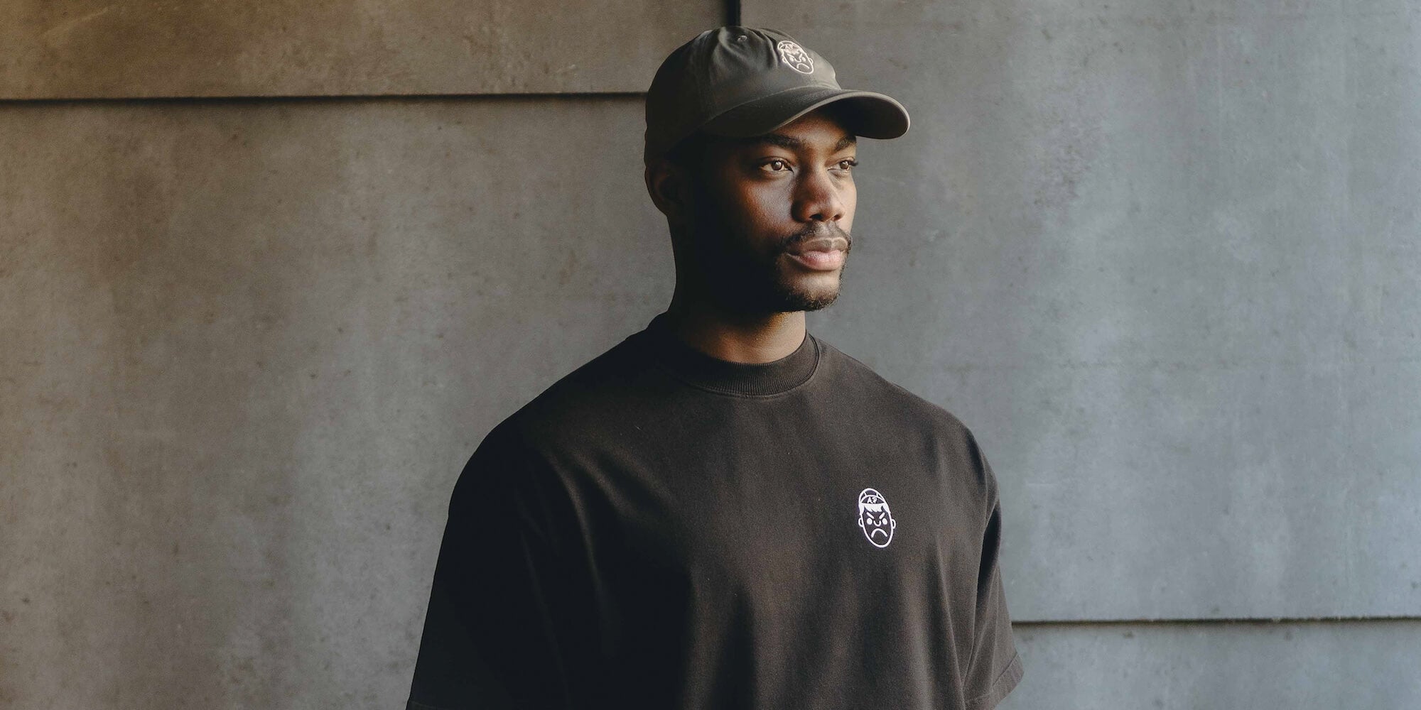 A man wearing a black heavy oversized t-shirt and an Angry Pablo performance cap.