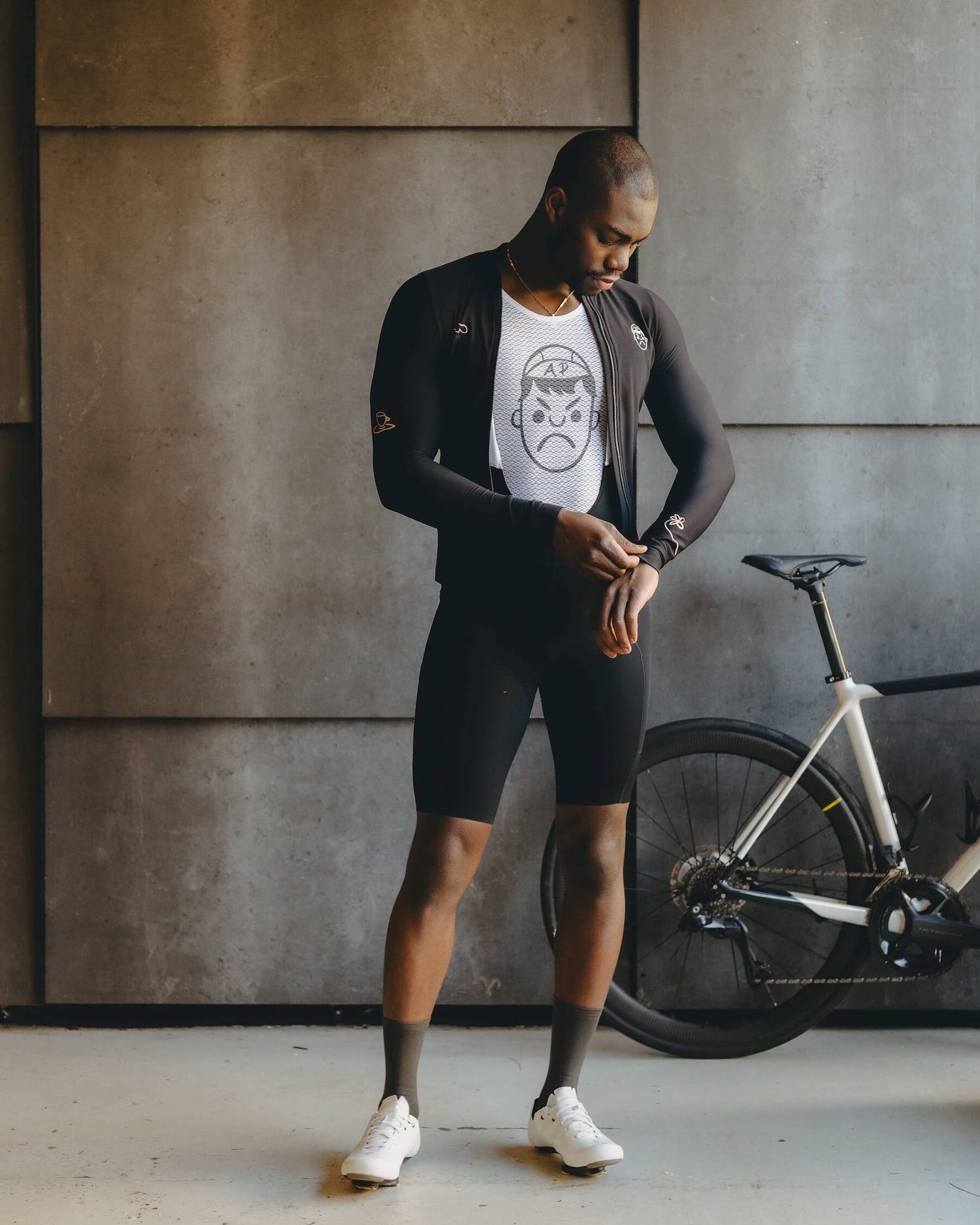 A model wearing an Angry Pablo cycling base layer with a bike in the background