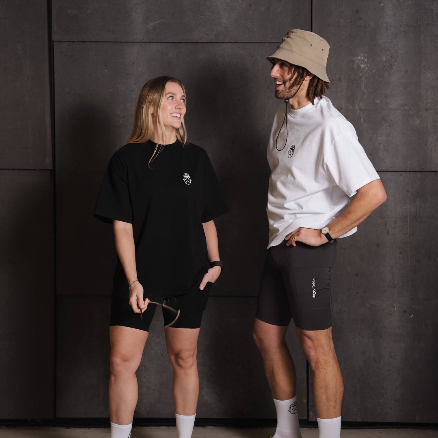 A man and woman smiling whilst wearing Angry Pablo Heavy Oversized T-shirts and cycling bib shorts