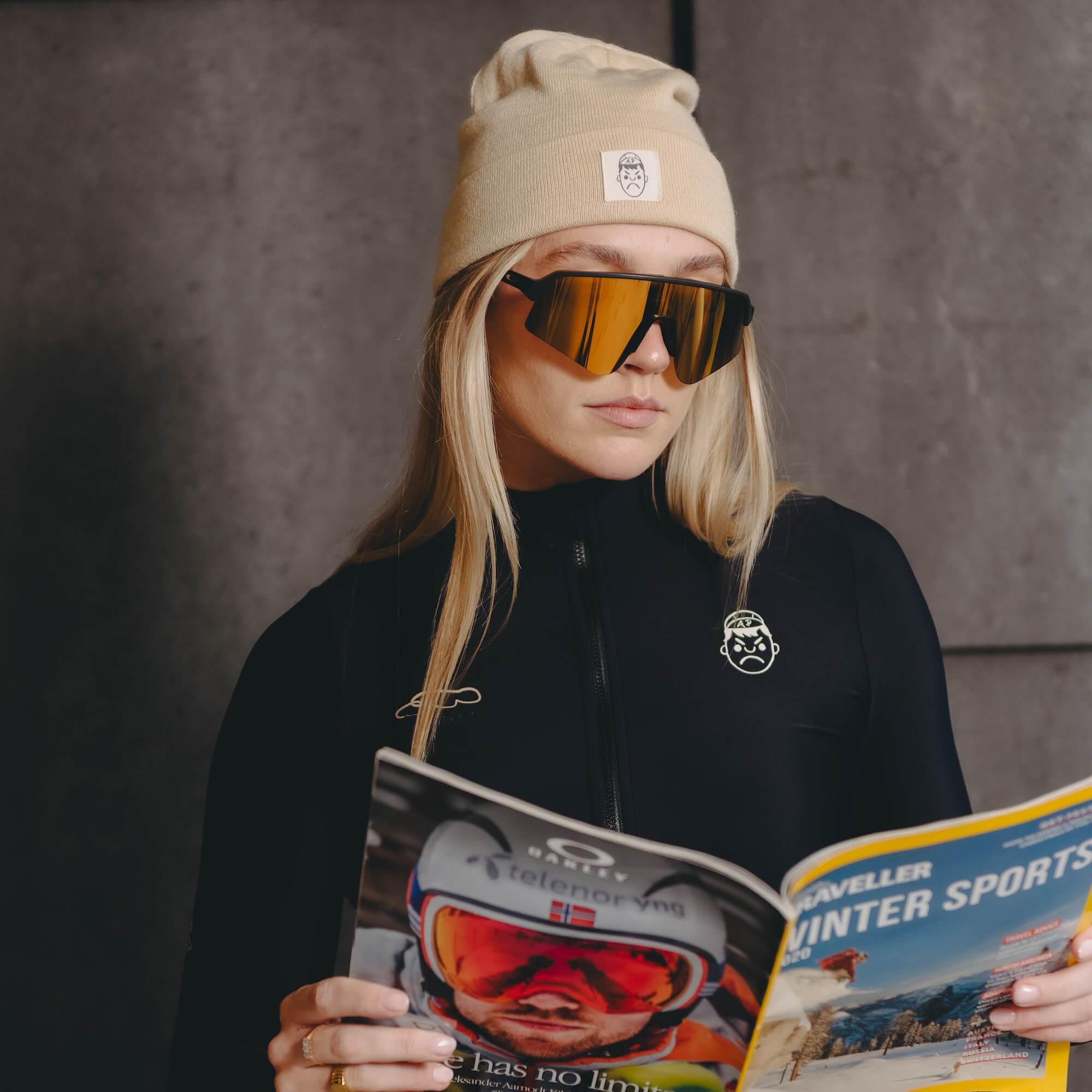 A female model reading a magazine whilst wearing an Angry Pablo Beanie and a black long sleeve cycling jersey